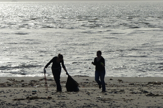photo of a beach clean, silhouettes in foreground