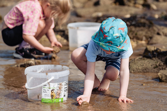 Two young children rockpooling on North Landing beach.