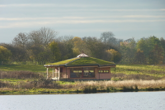Large pentagon shaped bird hide on the side of the lake at a nature reserve