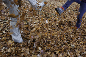 Two people kicking autumn leaves