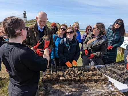 Staff member talking to a group of people at Spurn about oysters.