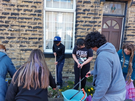 Group of youths gardening in an urban, residential front garden of a house