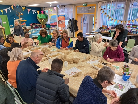 Group of people sat round a table making seagrass seed bags