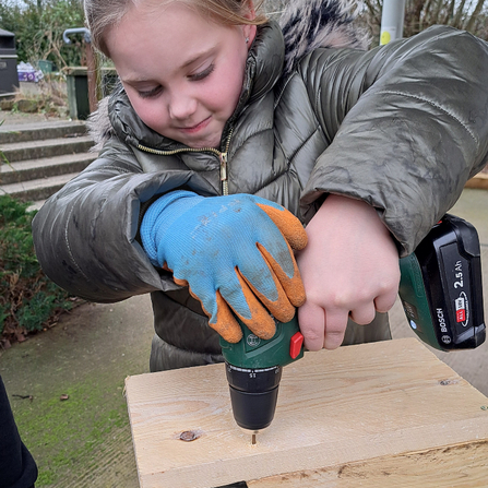 Girl being supervised using a drill to make a bird box