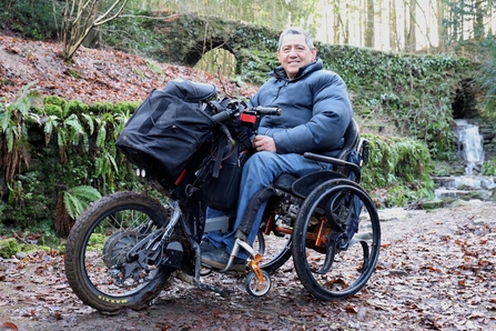 Man in a 3-wheeler all terrain mobility scooter on a nature reserve smiling for the camera