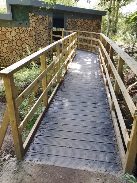 An accessible ramp up to a hide overlooking a lake on a nature reserve