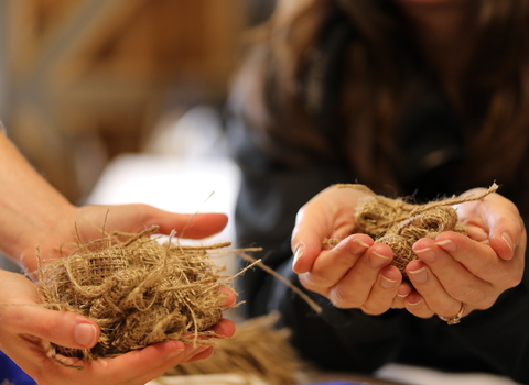 Seagrass hessian bags in the palms of two peoples' hands