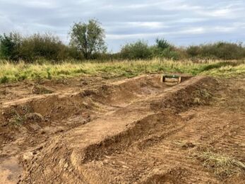 A channel formed out of soil with a small wooden sluice at the back