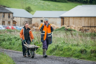 Stirley Farm volunteers, in high-vis with a wheelbarrow