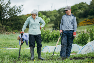 Jane and another volunteer standing in front of vegetable beds at Stirley