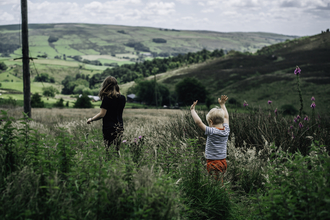 Two children running through a meadow