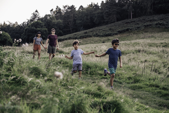 Two adults and two children running through a field