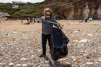 A young boy picking litter on Flamborough beach.