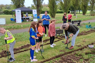 Group of people out in the park in their community digging bedding areas to plant for pollinators