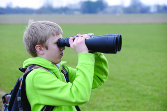 Boy looks through large binoculars