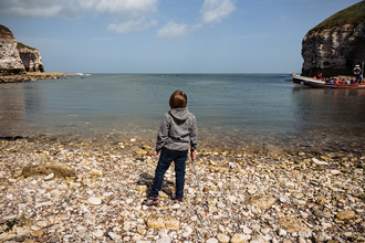 A young person staring out to the sea from the beach at Flamborough