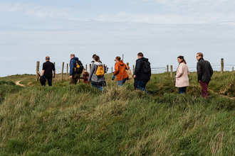 A group of people on a guided walk, following a leader on a path.