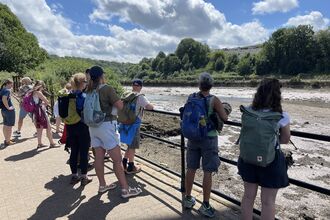A group of people on a guided walk look out of the River Esk 