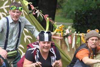 A group of actors dressed as wind in the willows characters creep forward mid performance.