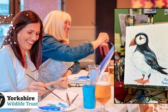 Image shows two people painting in a relaxed setting as well as a painted puffin on a canvas