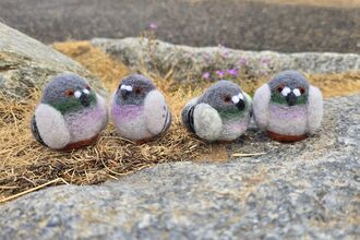 4 felted pigeons sit outside on a rock.