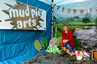 A lady sits by some painted toadstool props in a gazebo 