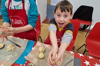 A child excitedly rolls balls of dough