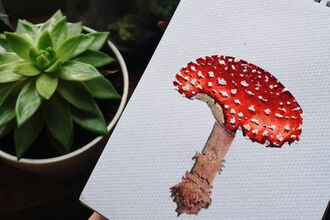 A red and white toadstool painting next to a potted plant