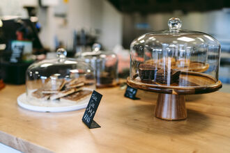 Sweet treats in glass domed cases on display for people to buy. 