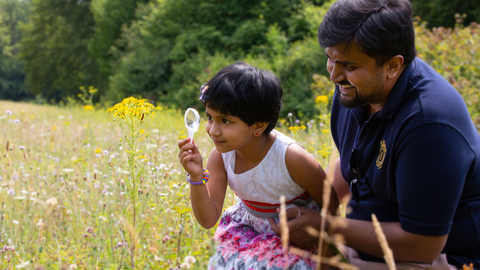 Family in field with magnifying glass