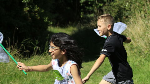 A little girl and a boy run with nets