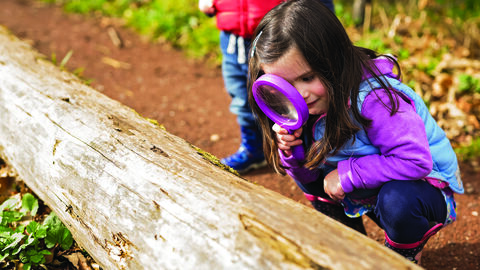 Young girl looking through a magnifying glass 