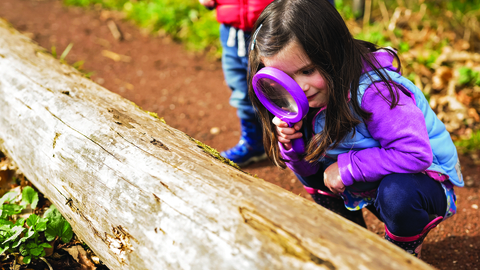 Young girl looking through a magnifying glass 