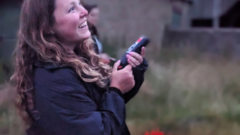 A young woman holds out a bat detector