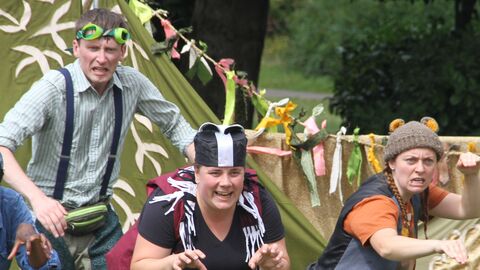 A group of actors dressed as wind in the willows characters creep forward mid performance.