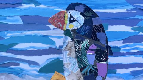 Collage puffin in foreground and collage textured blue sea and golden sand behind