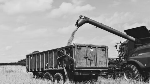 Black and white image showing a tractor harvesting a field