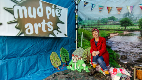 A lady sits by some painted toadstool props in a gazebo 