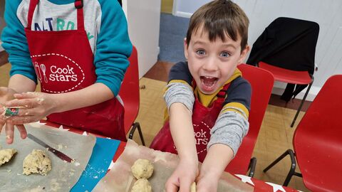 A child excitedly rolls balls of dough