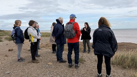 A group of people at a beach at Spurn listening to Milissa