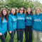 Five individuals wearing matching teal hoodies that say "I'm part of Team Wilder" stand in front of a white-flowered bush and green grass.