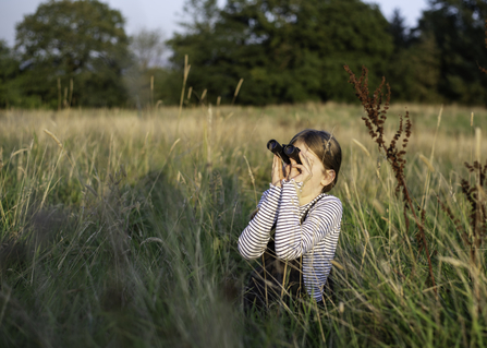 Child with binoculars in field