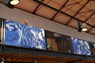 Artist Jacqui Barrowcliffe with the Wild Eye seaweed cyanotype banners in Scarborough Market Hall.