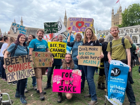 group of people in a demonstration on the streets of London gathered in a group for the camera holding their handmade banners asking to restore nature now