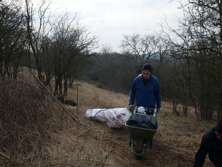 Volunteer pushing tea across site in a wheelbarrow