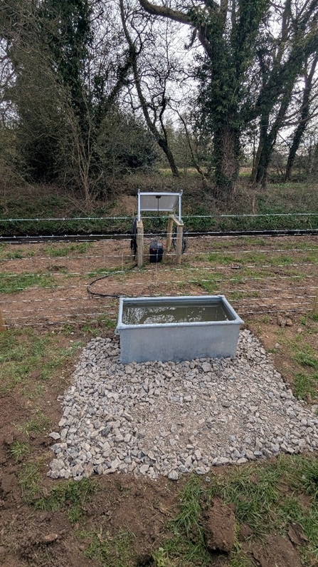 A brand new rectangular drinking trough with hard gravel standing.