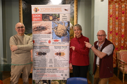 Members of Yorkshire Beekeepers Association standing next to a poster about invasive hornets