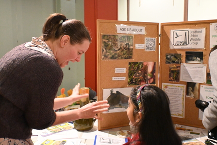 Woman next to information child explaining something to a girl