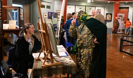 Person dressed as a Green Man standing by a stall