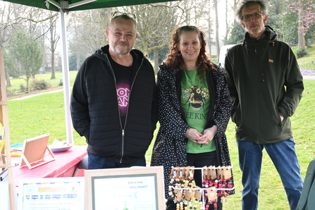 Three people standing under a gazebo with information stand
